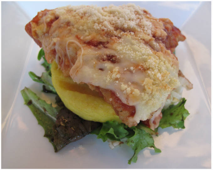 Finished chicken parmesan with polenta and a mixed-green salad