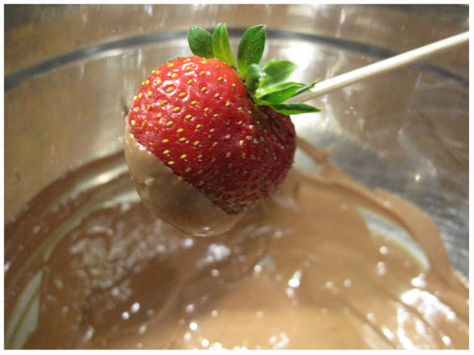 Dipping a strawberry into tempered chocolate
