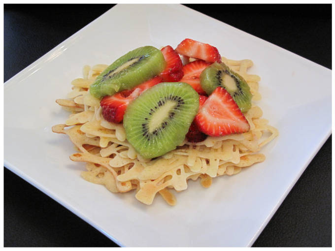 Orange lace pancakes with kiwi, strawberries, and maple syrup