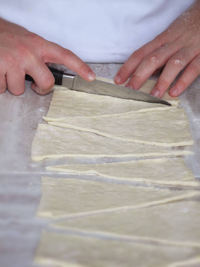 Cutting croissant dough to form triangles