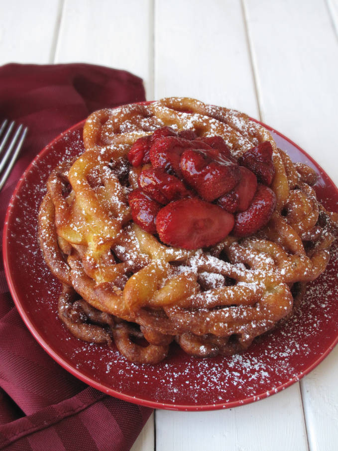 Fresh, homemade funnel cake with strawberries and icing sugar, just like at the carnival! Want a bite? The recipe is super simple! Click to get it.