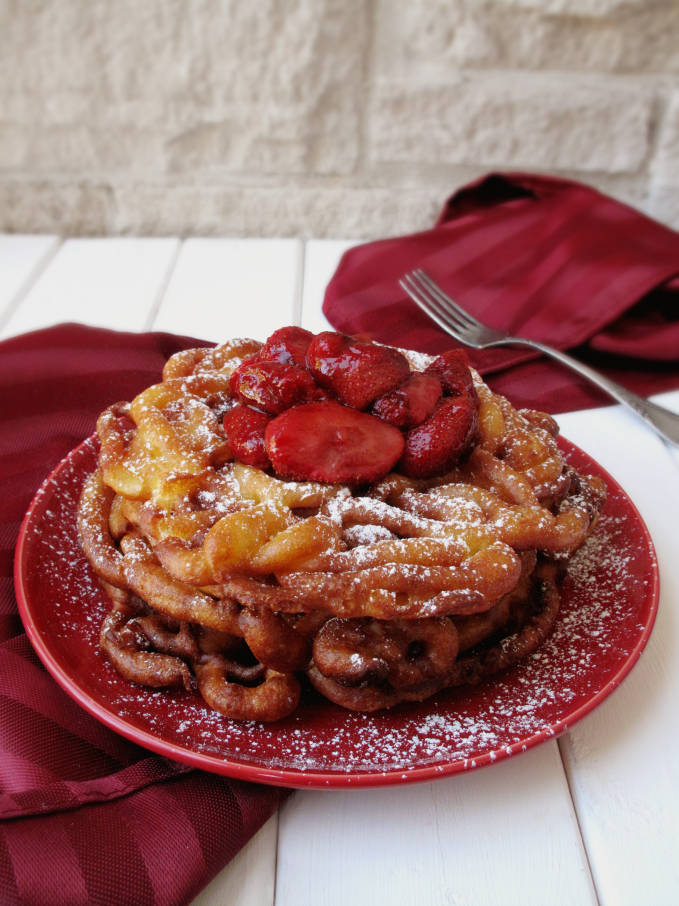 Fresh, homemade funnel cake with strawberries and icing sugar, just like at the carnival! Want a bite? The recipe is super simple! Click to get it.