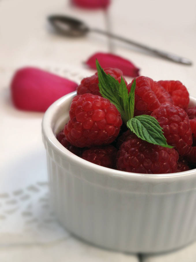 Raspberries with a sprig of mint and rose petals