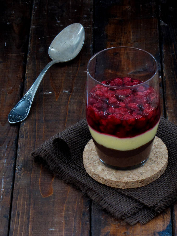 A cup of rich dark chocolate and creamy vanilla pudding with raspberry compote