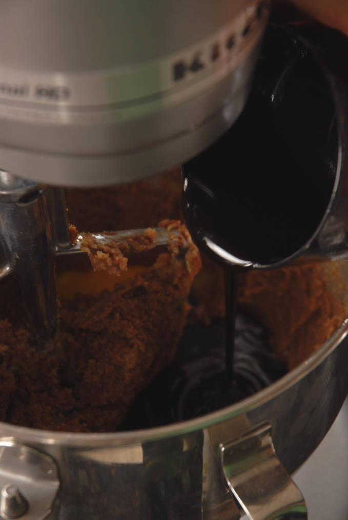 Pouring molasses into gingerbread dough. Click for a full photo tutorial on how to make amazing gingerbread! Perfect for the holidays #christmas