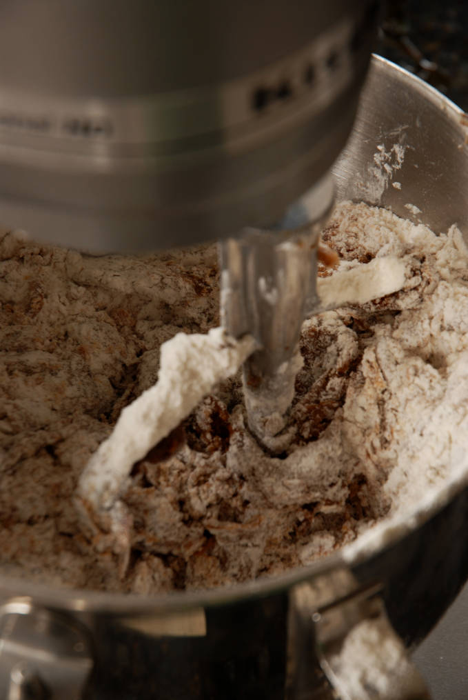 Mixing flour into wet gingerbread dough. Adding flour to gingerbread dough. Click for a full photo tutorial on how to make amazing gingerbread! Perfect for the holidays #christmas