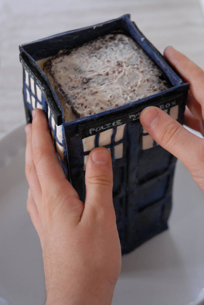 Attaching TARDIS cake sides--click to see the full photo tutorial so YOU CAN MAKE YOUR OWN DOCTOR WHO TARDIS CAKE! #diy