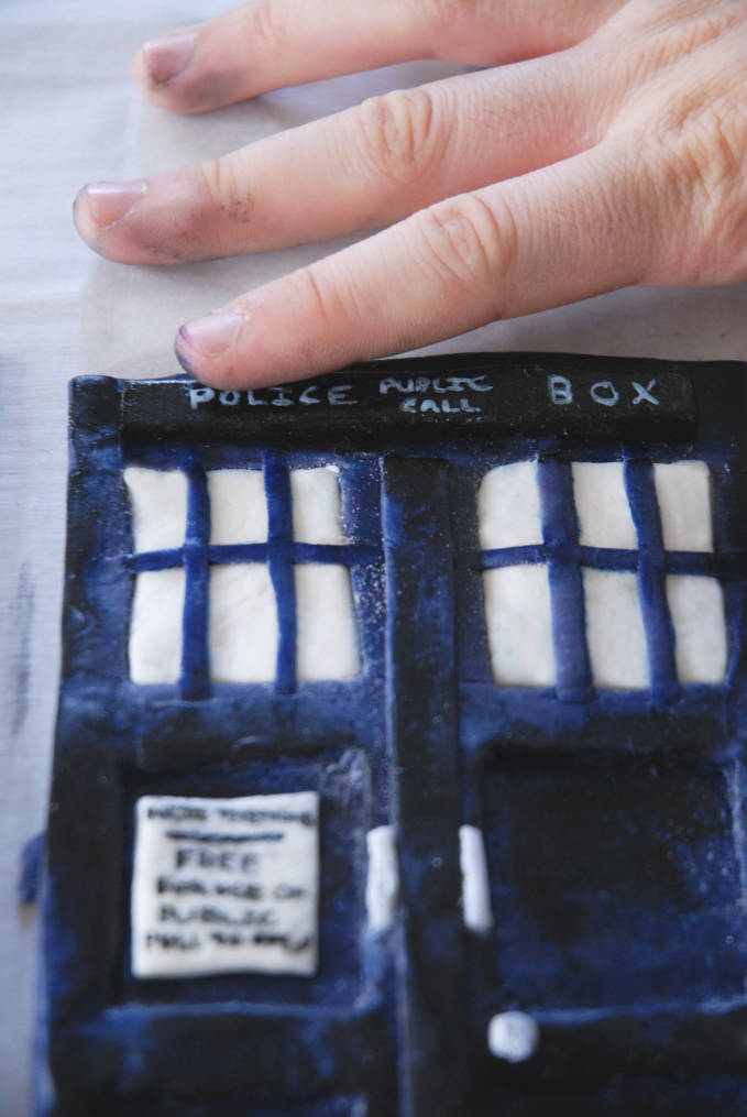 Attaching police public call box sign to Doctor Who TARDIS cake--click to see the full photo tutorial so YOU CAN MAKE YOUR OWN DOCTOR WHO TARDIS CAKE! #diy