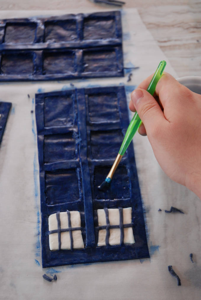 Painting the Doctor Who TARDIS cake sides with blue and black food colouring--click to see the full photo tutorial so YOU CAN MAKE YOUR OWN DOCTOR WHO TARDIS CAKE! #diy