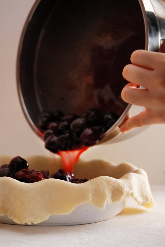 Adding cherry pie filling to a pie crust--click to get a step-by-step photo tutorial on lattice pie crusts, so you can make them easily!