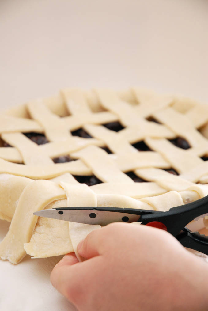 Cutting off extra pie dough ensures a nice edge--click to get a step-by-step photo tutorial on lattice pie crusts, so you can make them easily!