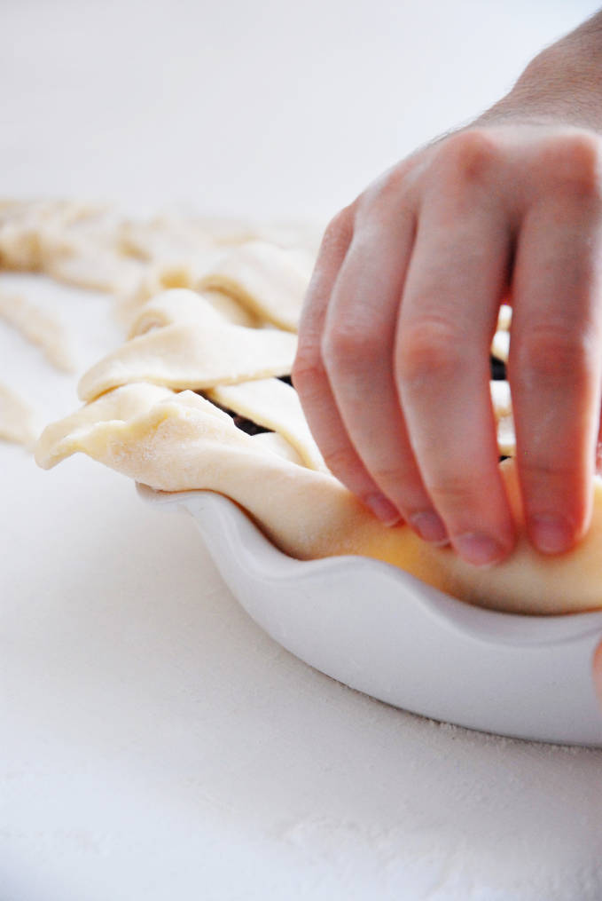 Folding the edges of the pie dough helps prevent the pie from falling apart when baking--click to get a step-by-step photo tutorial on lattice pie crusts, so you can make them easily!