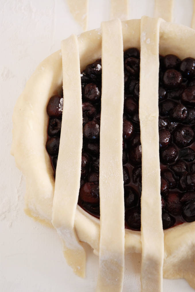 Adding strips of pie dough to a pie to make a lattice crust--click to get a step-by-step photo tutorial on lattice pie crusts, so you can make them easily!