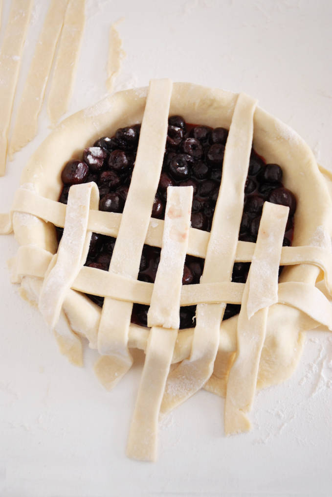 Adding strips of pie dough to a pie to make a lattice crust--click to get a step-by-step photo tutorial on lattice pie crusts, so you can make them easily!