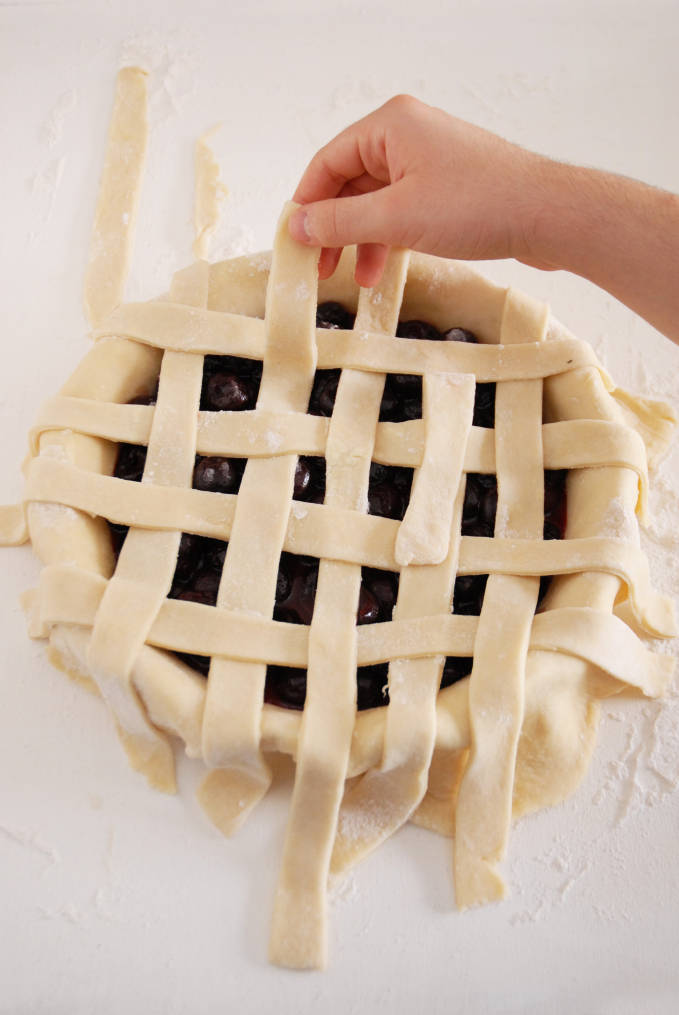 Adding strips of pie dough to a pie to make a lattice crust--click to get a step-by-step photo tutorial on lattice pie crusts, so you can make them easily!