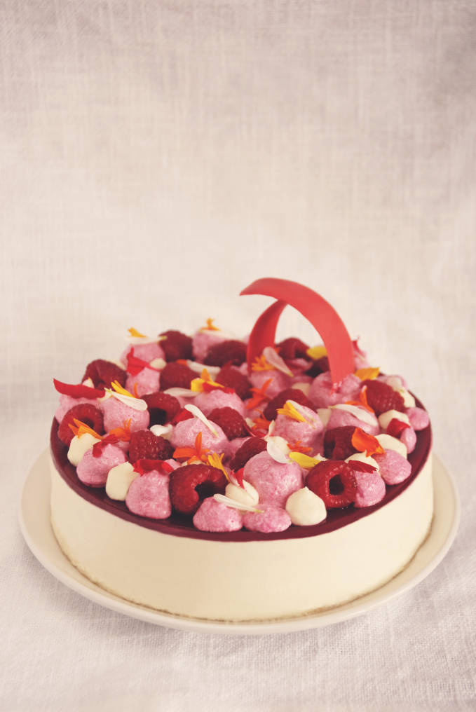 Raspberry and white chocolate entremet with almond dacquoise, white chocolate mousse, raspberry gel, raspberry mousse, whipped white chocolate and coconut ganache, fresh raspberries, and edible flowers. Click to get the recipe!