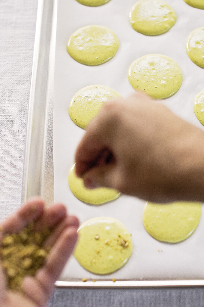 Topping French macarons with pistachios before baking